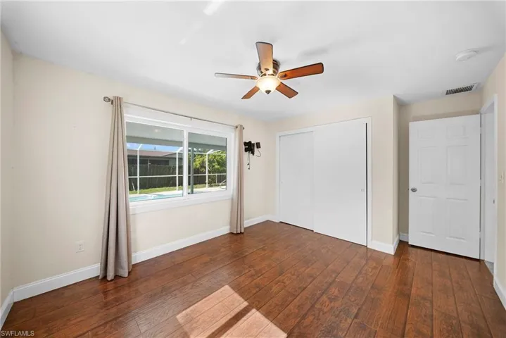Room featuring wood-finish flooring, a ceiling fan with integrated lighting, and a large window