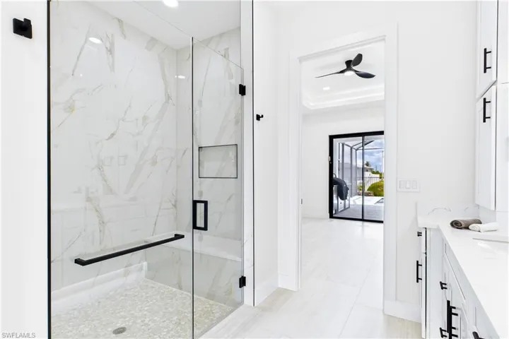 LUXURIOUS PRIMARY BATHROOM w/ spacious WALK-IN GLASS SHOWER w/ floor-to-ceiling designer tile, rainfall showerhead, built-in bench & modern matte-black fixtures