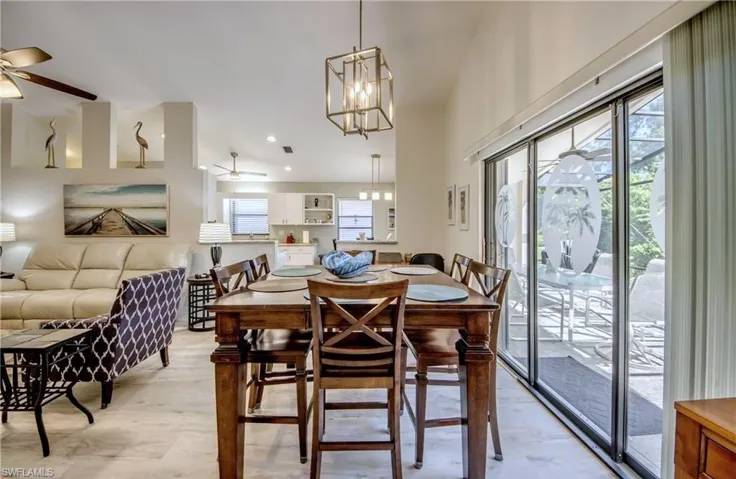 Living Room and Dining space in the great room featuring plenty of natural light, ceiling fan with notable chandelier, and sliders to the expanded lanai