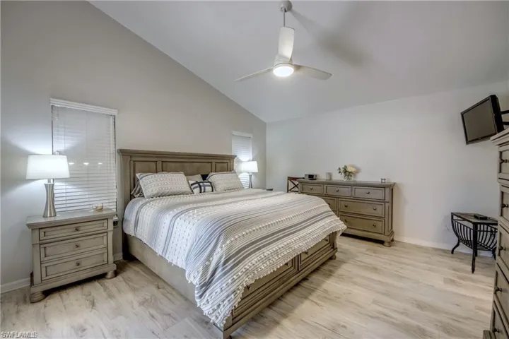 Bedroom with high vaulted ceiling, ceiling fan and matching flooring to the rest of the home