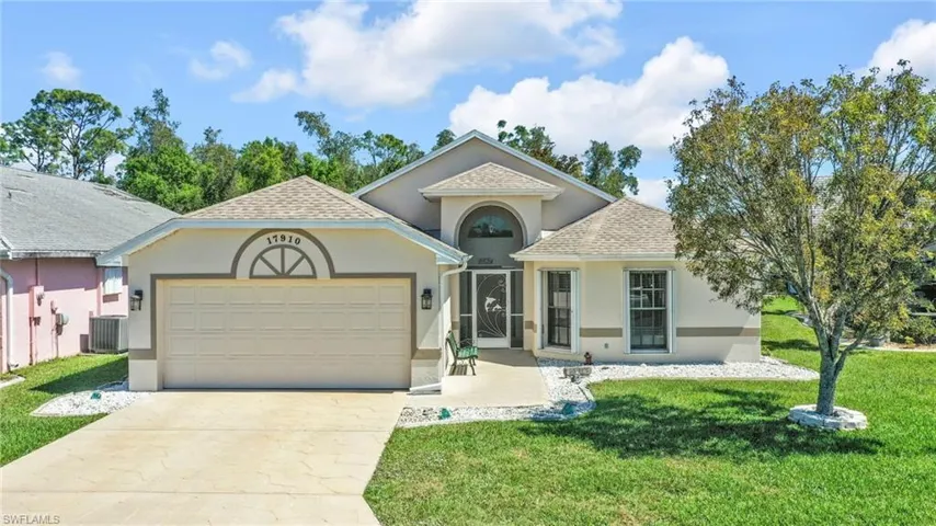 View of front of home featuring a front lawn, concrete driveway, roof with shingles, stucco siding, and an attached garage
