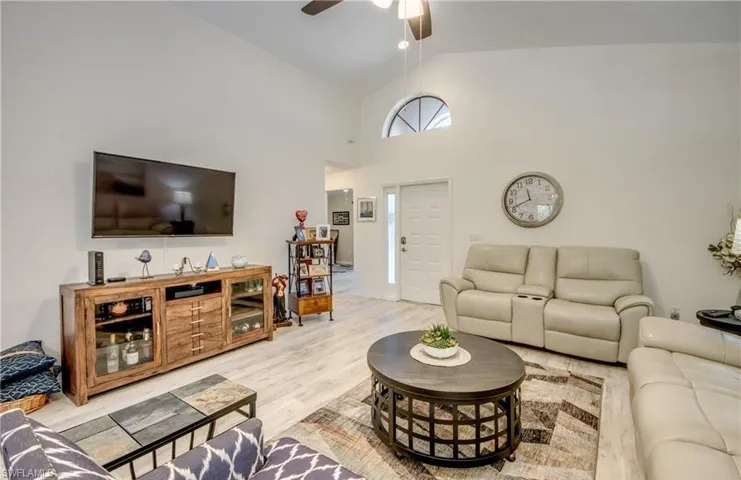 Living room featuring high vaulted ceiling, wood finished floors, and a ceiling fan