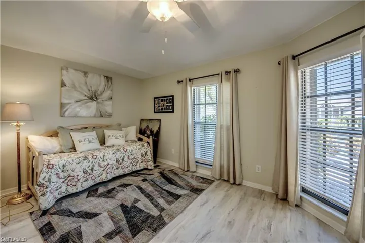 Den featuring floor length windows with neutral curtains, and updated ceiling fan