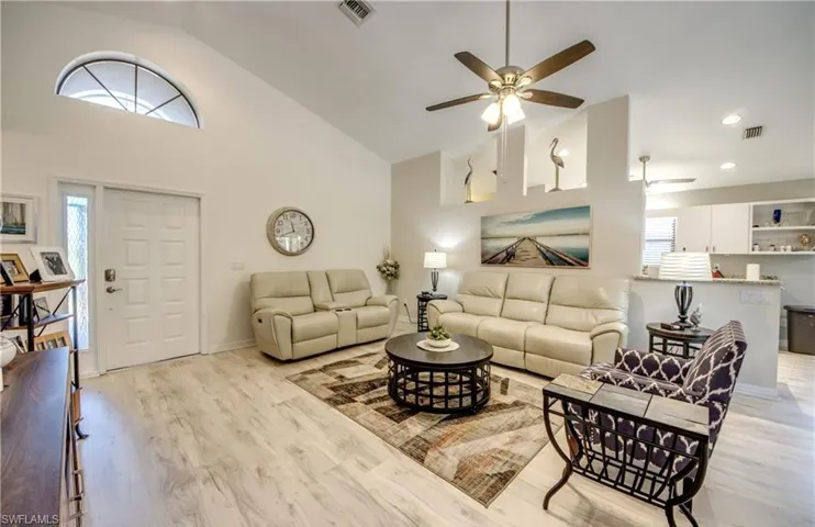 Living room featuring visible vents, light wood-style floors, ceiling fan, and high vaulted ceiling
