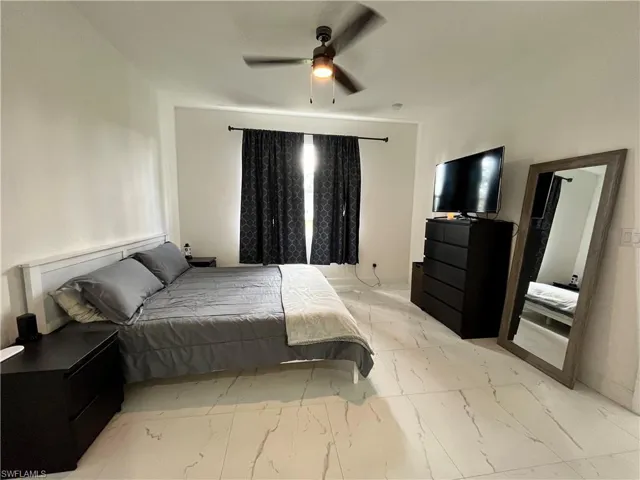 Bedroom with light marble finish floors and a ceiling fan