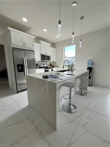 Kitchen with white cabinets, recessed lighting, refrigerator, stove, and marble finish floor
