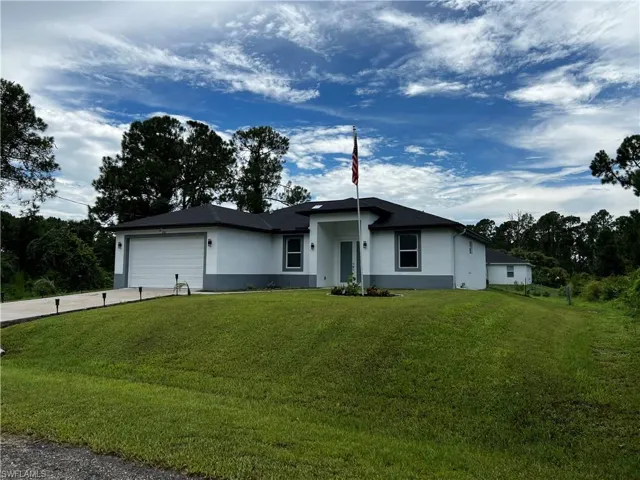 View of front facade with a garage, stucco siding, concrete driveway, and a front yard