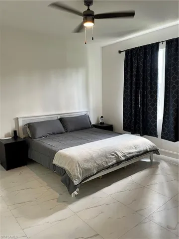 Bedroom featuring marble look tiles and ceiling fan
