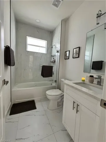 Full bath with vanity, shower / bathtub combination, and light marble finish flooring