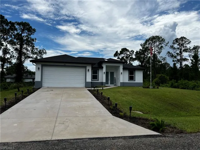 View of front facade with an attached garage, driveway, a front yard, and stucco siding