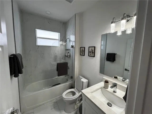 Bathroom with marble finish floor, toilet, vanity, and shower / bath combination