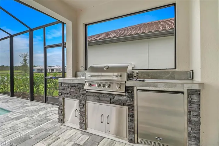 View of patio / terrace featuring glass enclosure, area for grilling, an outdoor pool, a sunroom, and a residential view