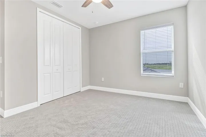 Unfurnished bedroom featuring light carpet, a closet, and a ceiling fan
