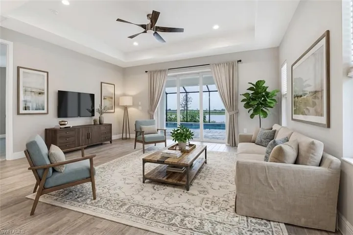 Living room featuring ceiling fan, light wood-style floors, a tray ceiling, and recessed lighting