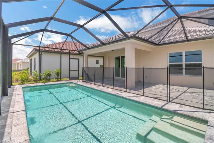 Outdoor pool featuring a sunroom, glass enclosure, and a patio area