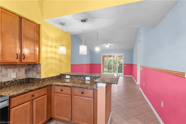 Kitchen featuring wood cabinetry, stone countertops, and a tile backsplash