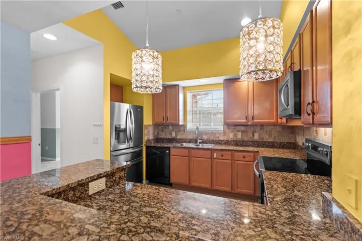 Kitchen featuring brown cabinetry, stainless steel appliances, and granite countertops