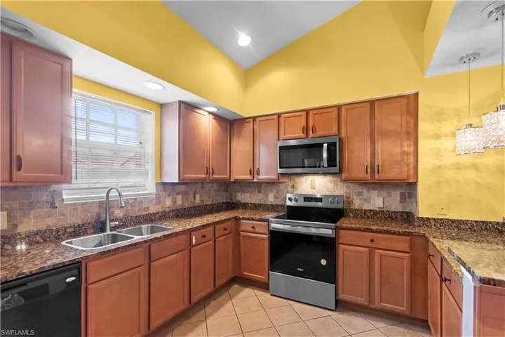 Kitchen featuring warm-toned cabinetry, granite countertops, and a tiled backsplash