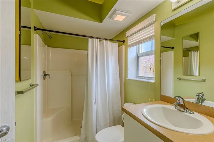 Bathroom featuring a shower/tub combination, single vanity with laminate countertop, chrome fixtures, and a window with blinds