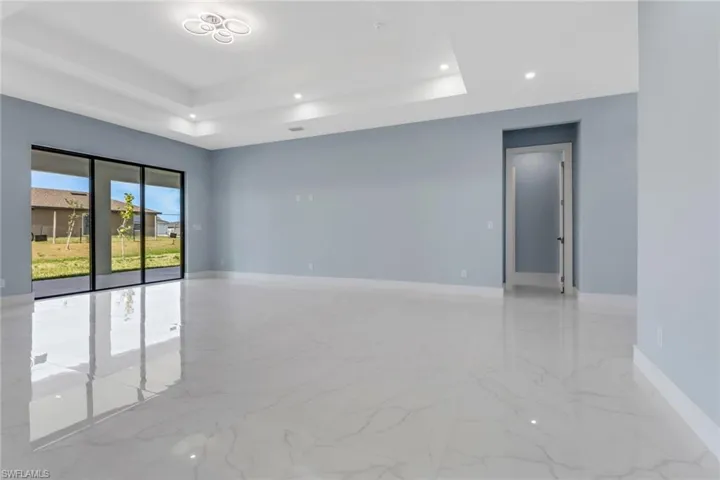 Unfurnished room featuring baseboards, a tray ceiling, recessed lighting, and marble finish floor