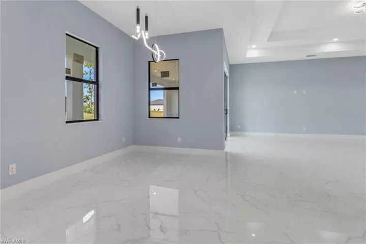 Spare room featuring baseboards, marble finish floor, and a notable chandelier