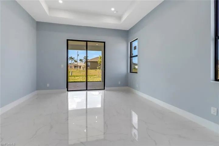 Spare room with a raised ceiling, recessed lighting, and marble finish floor