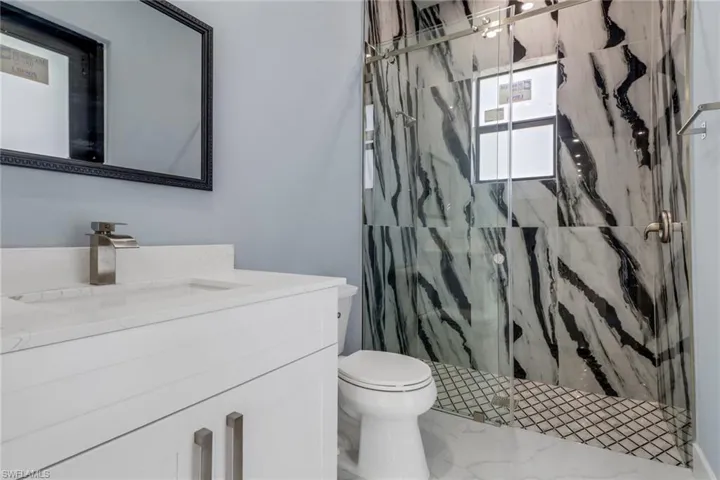 Full bathroom featuring toilet, a marble finish shower, and vanity