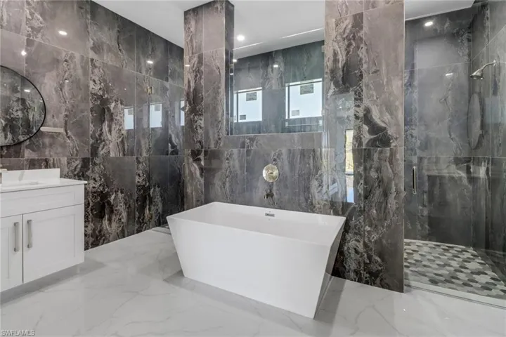 Full bath featuring a soaking tub, tile walls, a marble finish shower, and marble finish floor