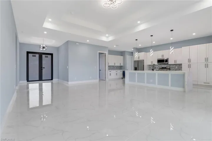 Unfurnished living room featuring recessed lighting, baseboards, a sink, and marble finish floor