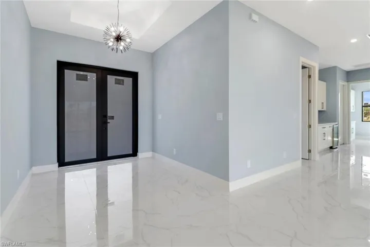 Foyer entrance with baseboards, recessed lighting, marble finish floor, and a chandelier