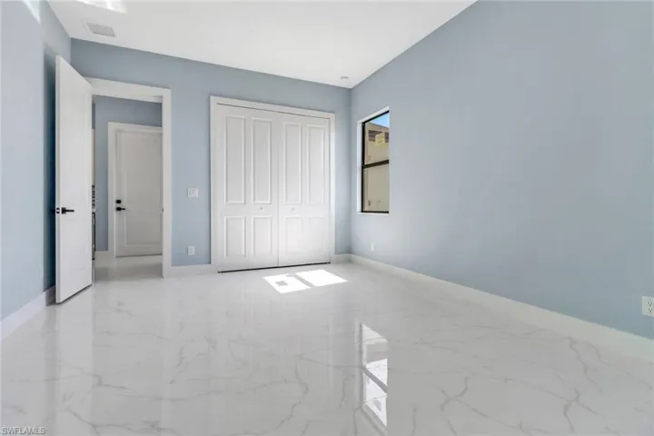 Unfurnished bedroom with visible vents, marble finish floor, baseboards, and a closet