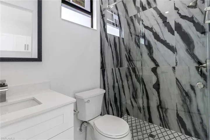 Full bathroom featuring toilet, a marble finish shower, and vanity