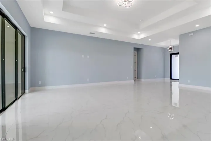 Empty room with recessed lighting, a tray ceiling, and marble finish floor