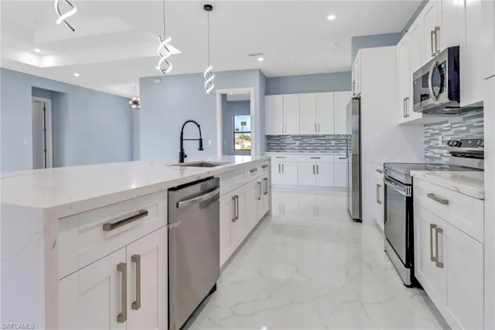 Kitchen featuring white cabinets, a sink, stainless steel appliances, recessed lighting, and decorative backsplash