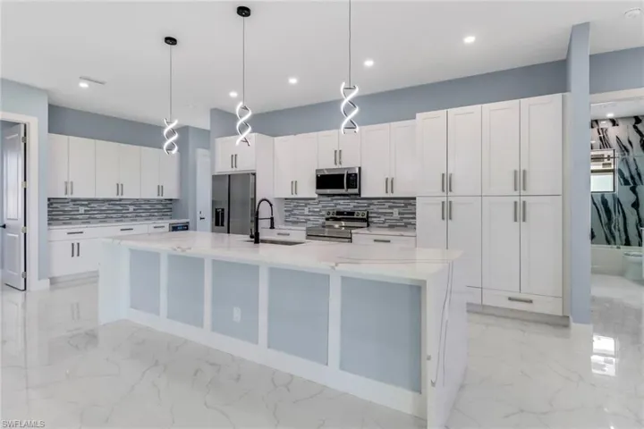Kitchen featuring a sink, marble finish floor, appliances with stainless steel finishes, and backsplash