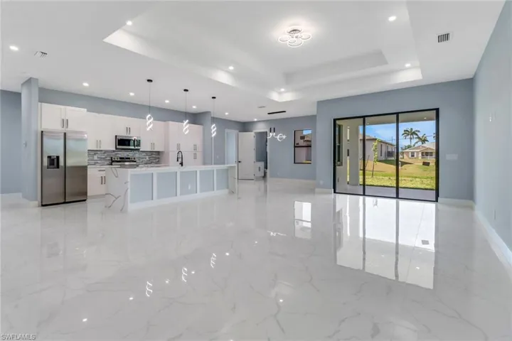 Unfurnished living room featuring recessed lighting, marble finish floor, and a tray ceiling