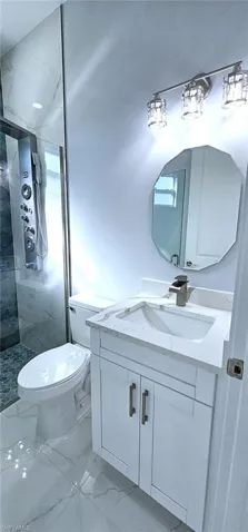 Bathroom with vanity, tiled shower, and toilet