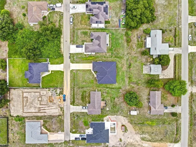 Aerial view of a residential street featuring multiple single-family homes and undeveloped lots