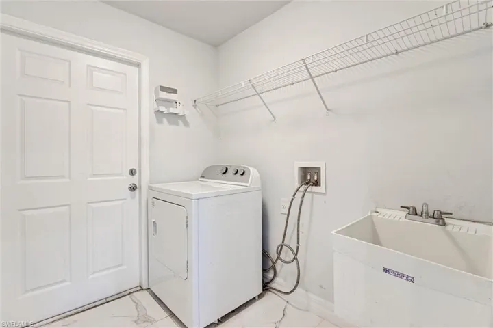 Utility room featuring a paneled door, wire shelving, and a utility sink