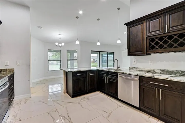 Kitchen featuring dark wood cabinetry, light-colored countertops with dark veining, stainless steel appliances, and a built-in wine rack