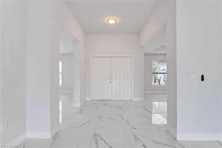 Entryway featuring large format marble-look tile flooring, white baseboards, and a contemporary flush-mount ceiling light