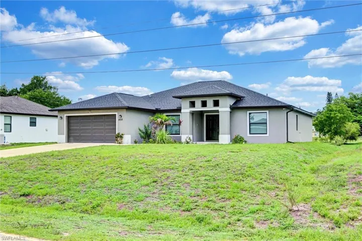 Contemporary gray stucco exterior featuring a dark asphalt shingle roof, a two-car garage with a dark brown door, and a covered entryway with decorative vertical accents