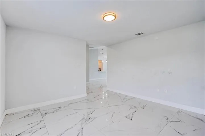 Spacious room featuring large format white tile flooring with dark veining and a contemporary ceiling light fixture