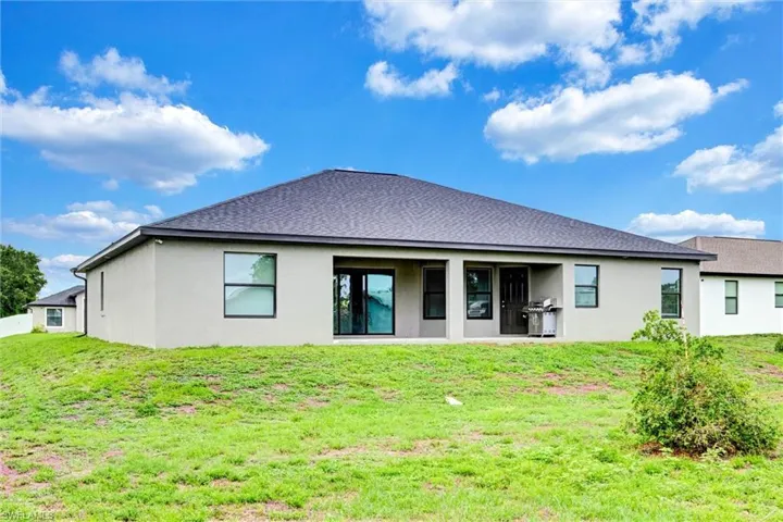 Contemporary stucco exterior with a dark shingle roof and a covered patio