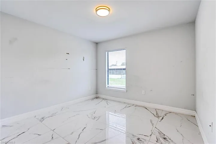 Room featuring large format tile flooring with distinctive veining, a single window, and a flush mount ceiling light fixture