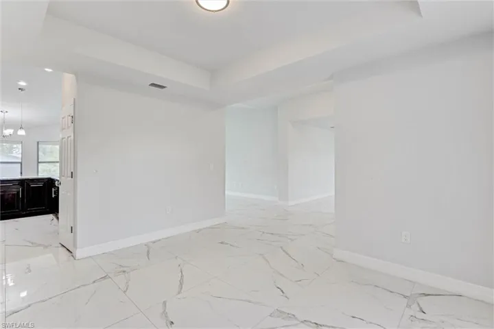 Spacious interior featuring large format tile flooring, white baseboards, and a tray ceiling with a flush-mount light fixture