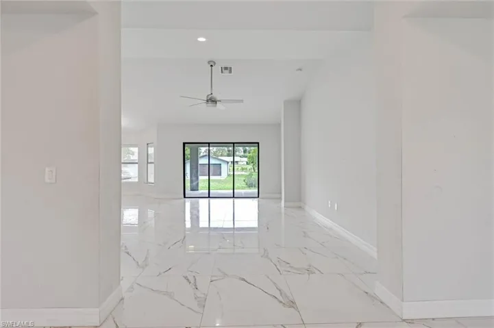 Spacious interior featuring white marble-look flooring, recessed lighting, and a modern ceiling fan