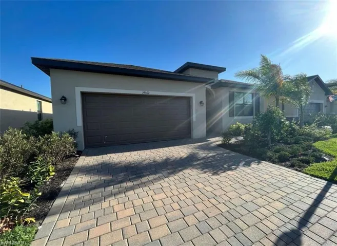 Single story home with decorative driveway, an attached garage, and stucco siding