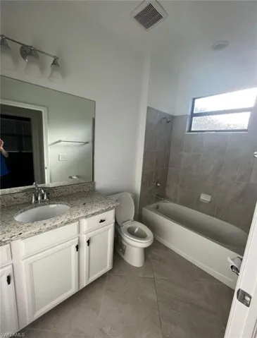 Bathroom with vanity, shower / bath combination, and light tile patterned flooring