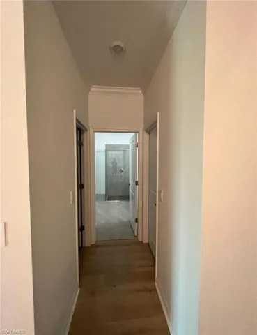 Hall featuring dark wood-type flooring and ornamental molding
